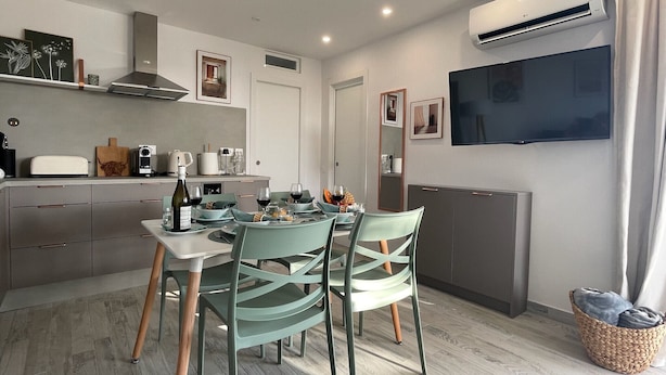 A modern kitchen with a dining area, a flat-screen TV, and an air conditioning unit. - Apartamerica Garden Apartment, 150 Metres From The (Playa de Las Americas)