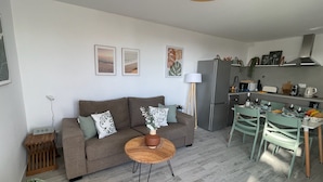 A modern living room with a sofa, a dining table with chairs, a kitchen area, and a decorative vase. - Apartamerica Garden Apartment, 150 Metres From The (Playa de Las Americas)