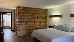 Un dormitorio con pared de madera, una cama con ropa de cama blanca y una mesita de noche.