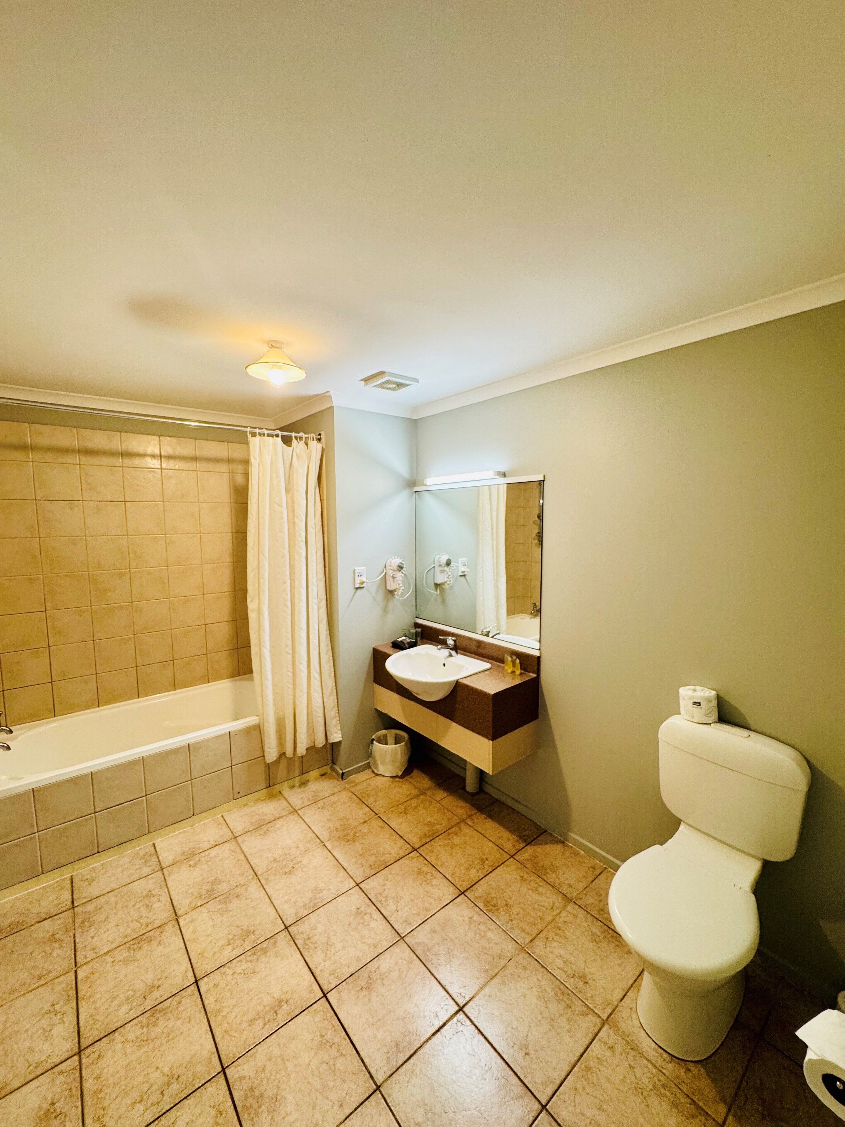 A bathroom with a bathtub, sink, mirror, and toilet.