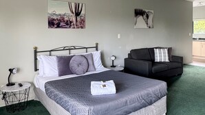 Un dormitorio moderno con una cama grande, un sofá y dos obras de arte colgadas en la pared.
