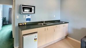 Una kitchenette compacta con microondas, pileta y un refrigerador pequeño.