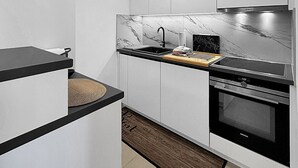 Eine moderne Küche mit weißen Schränken, einer schwarzen Arbeitsplatte, einer Marmor-Spritzschutzwand und einem Bosch-Ofen.