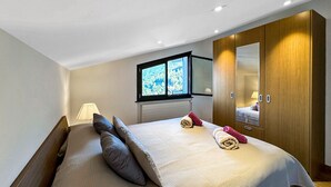 Ein Schlafzimmer mit Bett, Fenster, Kleiderschrank und Nachttisch mit Lampe.