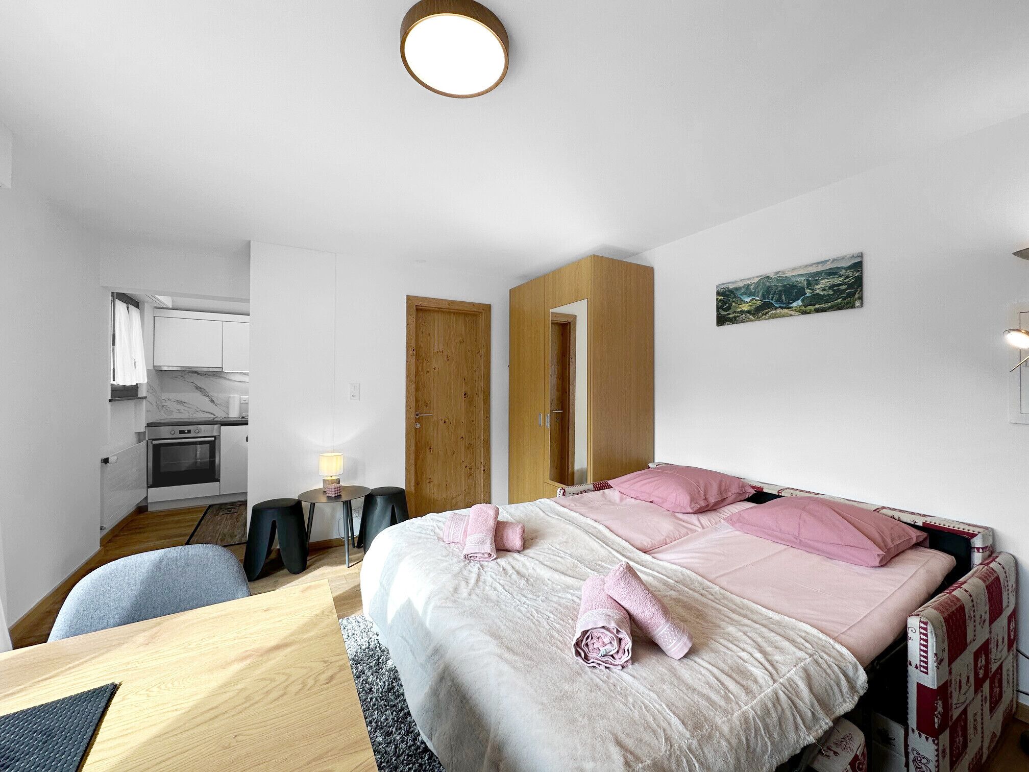 Une chambre compacte comprenant un lit, des tables de chevet, un bureau et un coin cuisine.