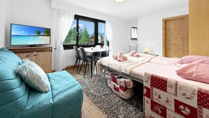Una habitación acogedora con cama, escritorio, televisor y ventana con vista a la playa.