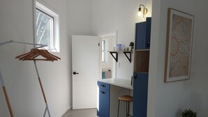 Une salle de bain moderne avec une porte blanche, un meuble-lavabo bleu, un tabouret en bois et un porte-serviettes suspendu.