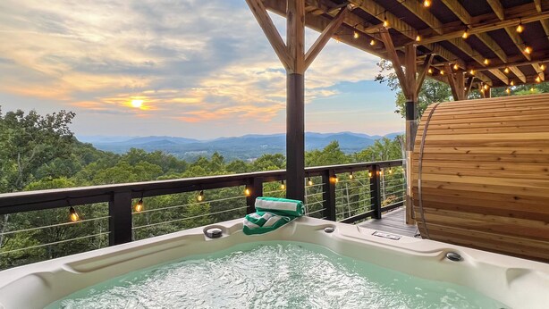 Un jacuzzi con vistas a montañas y al atardecer.