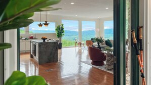 Amplia sala de estar con un ventanal que ofrece vistas panorámicas, una isla de mármol y mobiliario moderno.