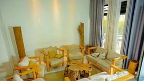 A room with wooden furniture, including sofas and chairs, arranged around a central wooden table. - Esspasso  (Musanze)