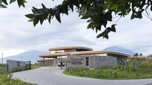 A modern building with a curved roof and a sign reading "The Ellen DeGeneres Campuses of the Dian Fossey Gorilla Fund." - Esspasso  (Musanze)