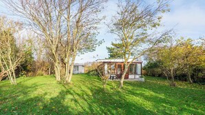 Ein modernes Haus mit Glasfassade, umgeben von einem gepflegten Rasen und Bäumen.