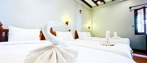 Una habitación de hotel con dos camas, un cabecero de madera, una lámpara de pared y una ventana.