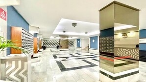 Eine Hotellobby mit Marmorboden, einer Rezeption und einer Treppe im Hintergrund.