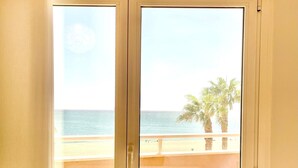Een kamer met uitzicht op de oceaan en palmbomen.