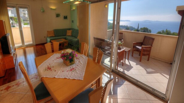 Un balcón con vistas al mar, un comedor con mesa y sillas, y un sofá.