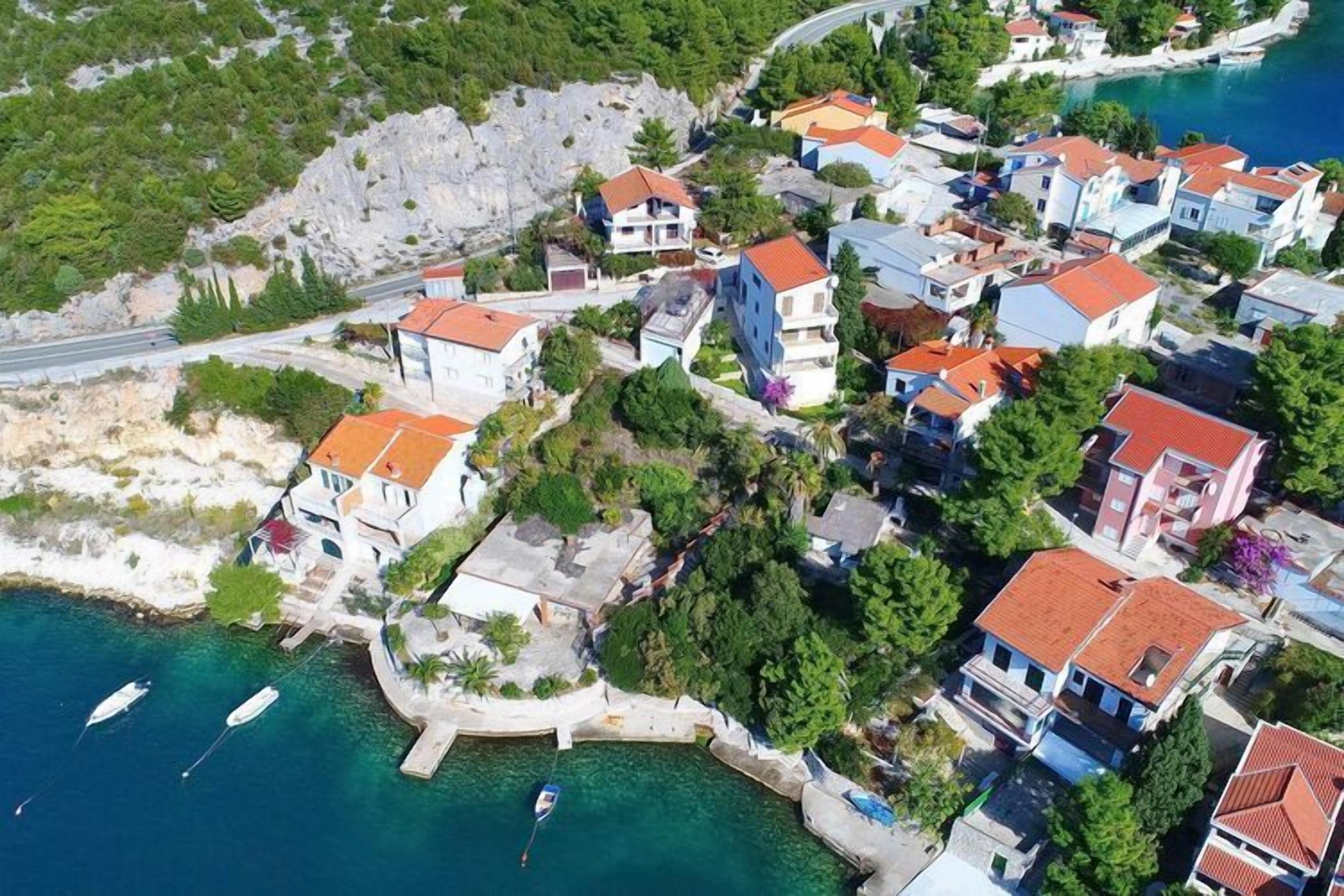 An aerial view of a coastal residential area with houses, a marina, and boats.