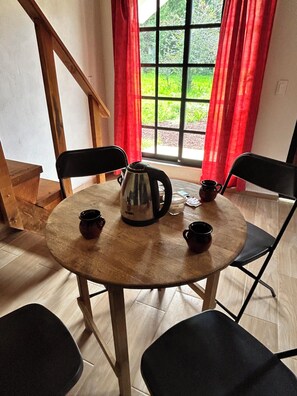 A round wooden table with four black chairs, a silver kettle, and two small cups. - Cabañas La Victoria By GEstores (Huasca de Ocampo)