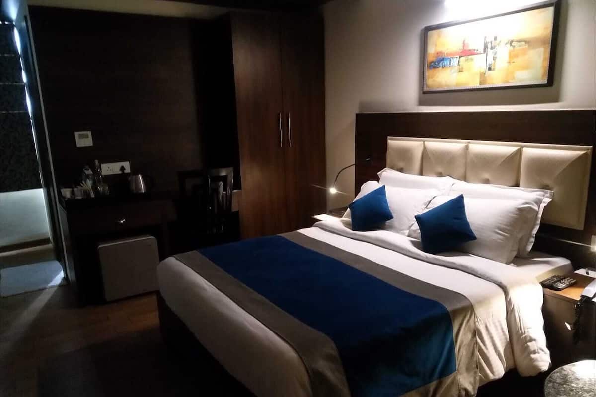 Habitación de hotel con cama, mesita de noche, lámpara y un cuadro en la pared.