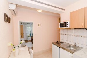 Een koelkast, een magnetron, een kookplaat, eettafels