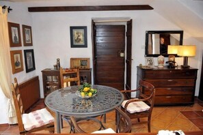 Un coin repas comprenant une table ronde en verre, des chaises, un meuble en bois et un miroir.