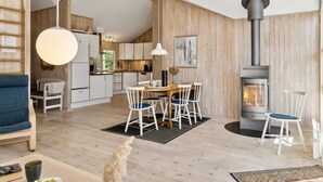 A modern kitchen with wooden accents, a dining area with a round table and chairs, and a wood-burning stove. - "Telse" - 200m from the sea by Interhome (Grenaa)