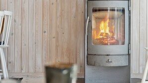 A modern room with a wood-burning stove, white furniture, and a wooden wall. - "Telse" - 200m from the sea by Interhome (Grenaa)