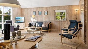 A modern living room with a wooden floor, a sofa, a dining table with chairs, a TV, and a large pendant light. - "Telse" - 200m from the sea by Interhome (Grenaa)