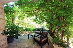An outdoor patio with a table and chairs, surrounded by lush greenery and vines. - Apartment Zorica - One Bedroom Apartment with Terrace (ST) (Supetar)
