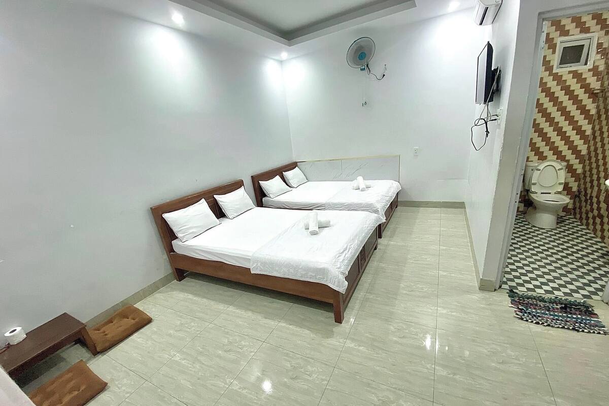 Una habitación de hotel con dos camas, un baño con piso a cuadros y un ventilador de techo.