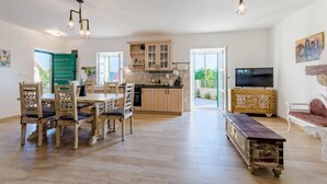 A spacious living area with a wooden dining table, chairs, a sofa, and a TV. - Holiday Home Rustic - Two Bedroom Holiday Home with Private Pool (Crivac)