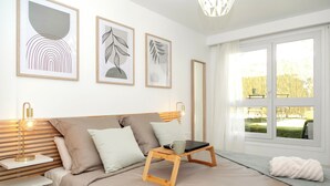 A bedroom with a bed, bedside table, lamp, and artwork on the wall.