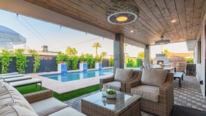 A covered outdoor area with a pool, wicker furniture, and a barbecue grill. - The Kensington| Luxe 4BR | Pool | Al-Fresco Living (Scottsdale)
