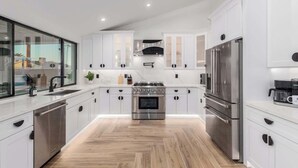 A modern kitchen with white cabinetry, stainless steel appliances, and a herringbone wood floor. - The Kensington| Luxe 4BR | Pool | Al-Fresco Living (Scottsdale)