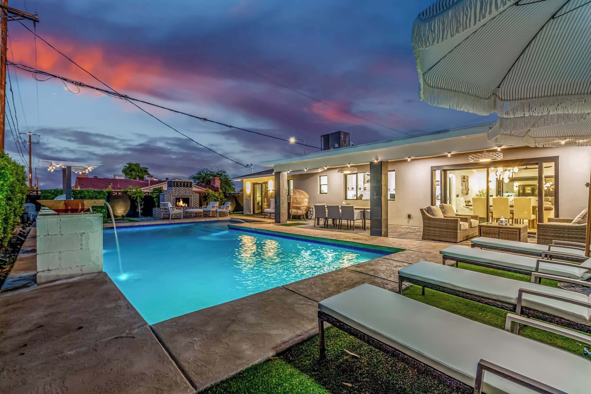 Un espace piscine extérieur moderne, doté d’une terrasse, de chaises longues et d’un coin repas.