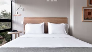 A modern hotel room with a large bed, a bedside table with a lamp, and a view of the outdoors through a window. - w* | Brilliant Loft near Parque 93 (Bogotá)