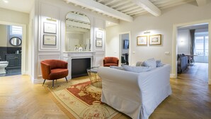 A spacious living room with a fireplace, a sofa, and a red armchair. There is a large mirror above the fireplace and a door leading to another room. - Beautiful apartment for 8 people with A/C, WIFI, TV and pets allowed (Florence)