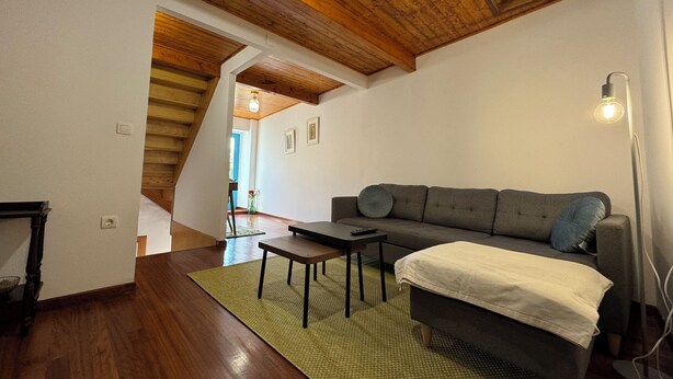 A cozy living room with a wooden ceiling, a sofa, a coffee table, and a lamp.