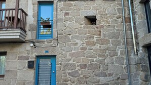 A stone building with a blue door and a balcony.