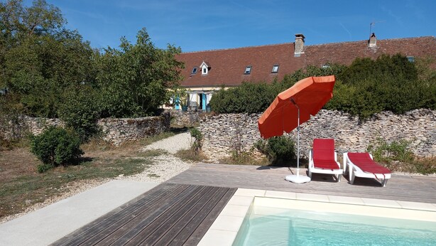 A pool area with wooden decking, two red lounge chairs, and a red umbrella. - Apartment with garden and pool near fabulous sights (Rocamadour)