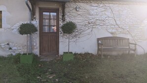 A rustic building with a wooden door, a stone wall, and a bench. - Apartment with garden and pool near fabulous sights (Rocamadour)