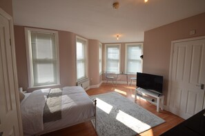 A bedroom with a bed, a TV, and large windows. - Studio in the Heart of Walthamstow Village (London)