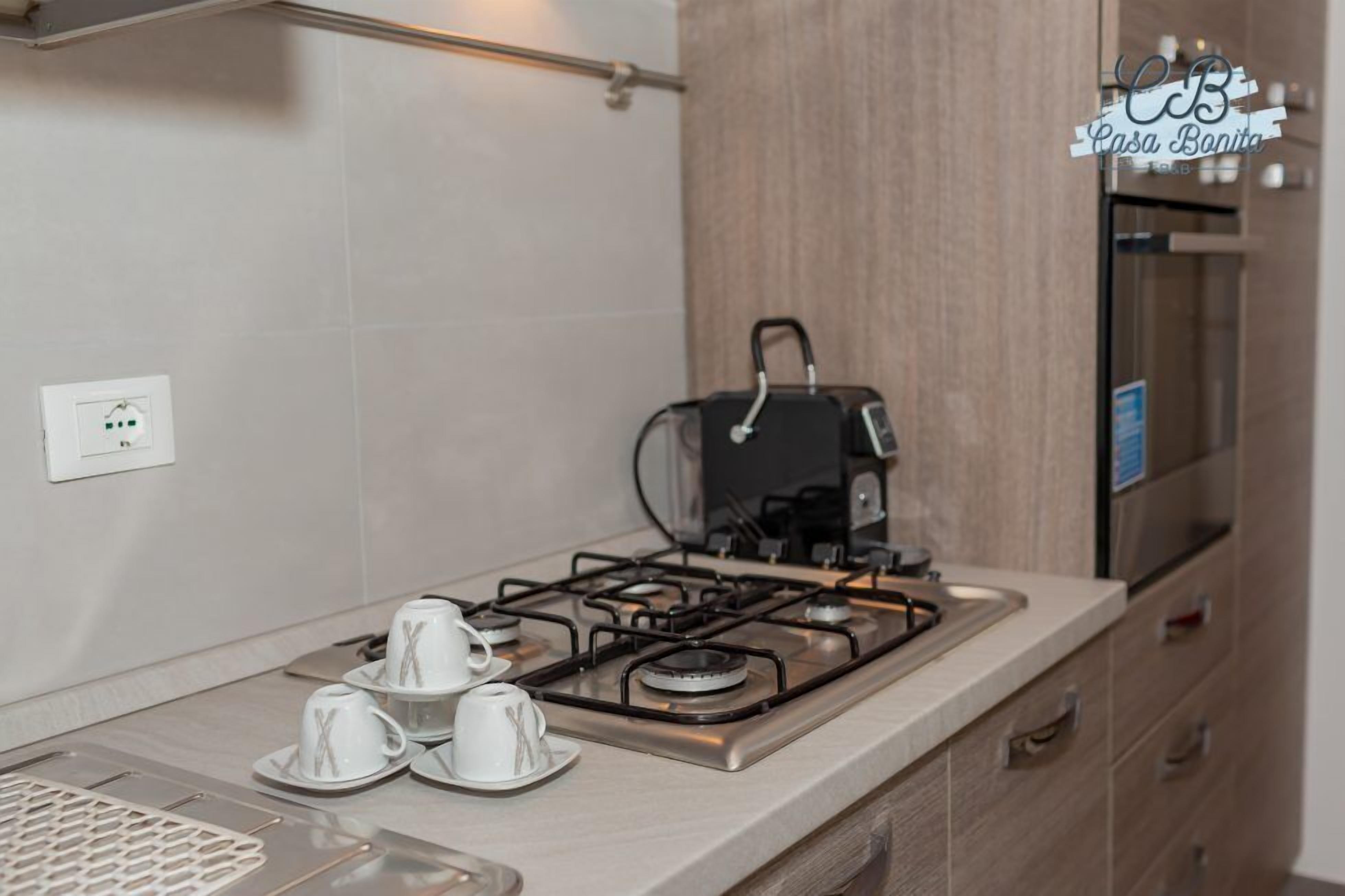 A modern kitchen with a gas stove, a coffee maker, and a refrigerator.