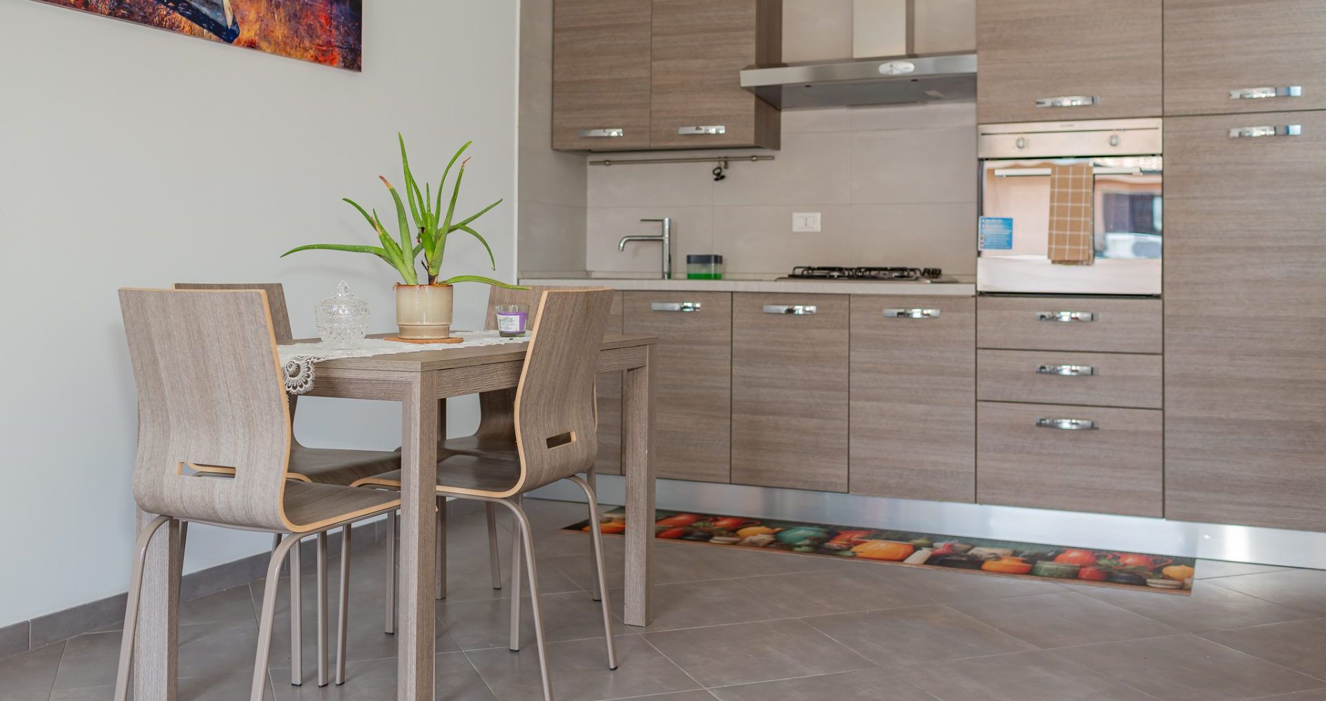 Una cocina moderna con armarios de madera, una mesa de comedor con sillas y una planta en maceta.