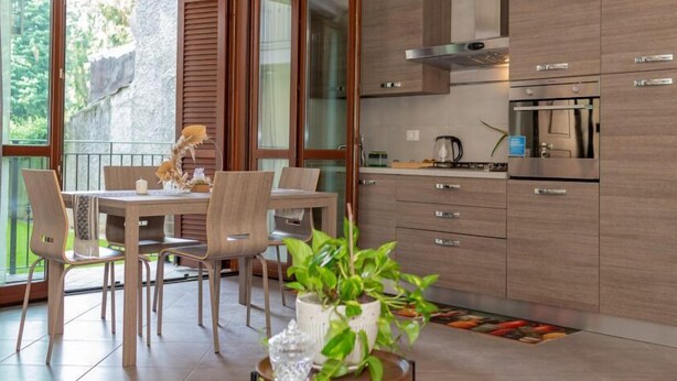Une cuisine moderne avec des meubles en bois, des appareils électroménagers en acier inoxydable et un coin repas comprenant une table et des chaises.