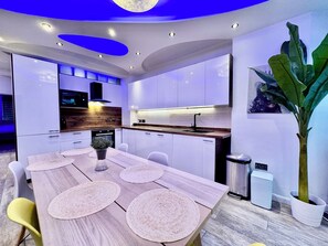 Una cucina moderna con mobili bianchi, un piano di lavoro in legno e un'area pranzo con tavolo e sedie in legno.