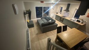 Una sala moderna con sofá, mesa de comedor y área de cocina con microondas y fregadero.