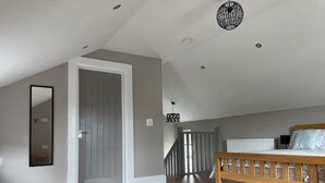 Un dormitorio con cama de madera, un espejo grande, una escalera y un candelabro en el techo.