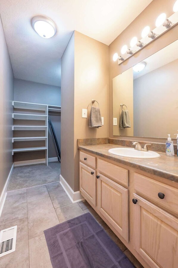 A bathroom with a vanity, a mirror, and a towel rack.