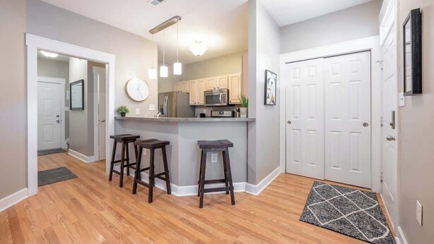 A modern kitchen with a central island, bar stools, and a microwave. - 6BR Downtown | Side-by-Side Townhomes | 2 Garages (Indianapolis)
